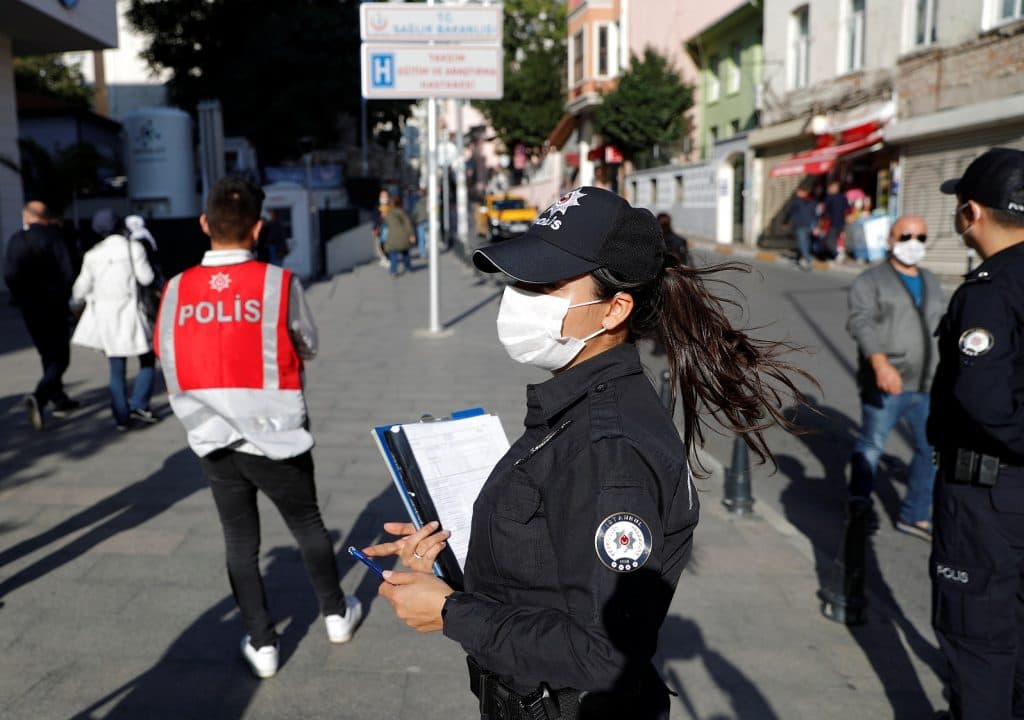 A police officer wearing a protective face mask checks if people wear them in Istanbul