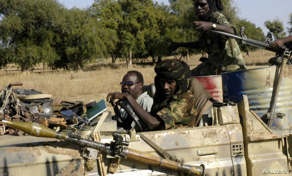 Sudanese SLA rebels watch as Africa Union armoured vehicles deploy in Muhajiriya